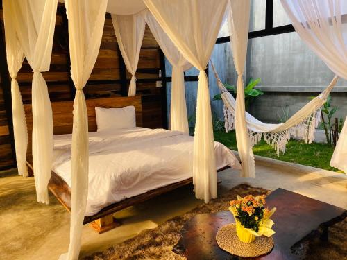 a bedroom with a bed with curtains and a table at Tiên Sơn Pleiku Homestay in Pleiku