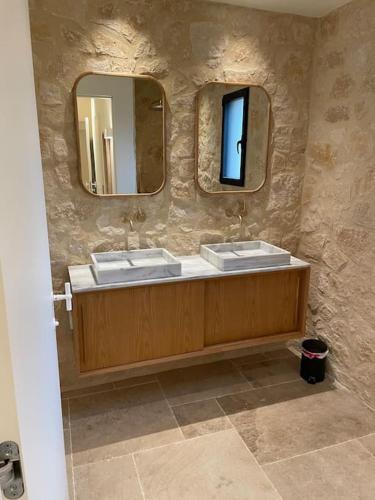 La salle de bains en pierre est pourvue de 2 lavabos et de 2 miroirs. dans l'établissement L'escapade dans le ciel, à Tourtour