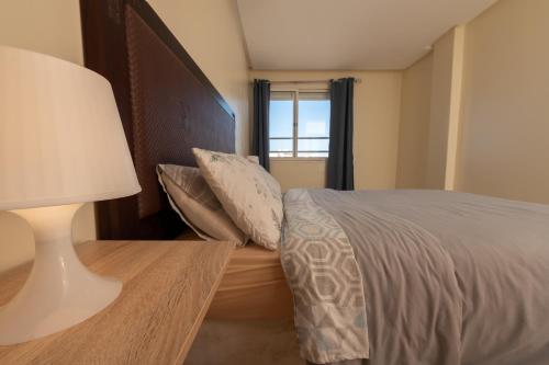 a bedroom with a bed and a lamp and a window at Appartement en résidence avec piscine in Agadir