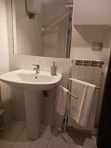 a white bathroom with a sink and towels at Casa vacanza Raffaela in Gubbio