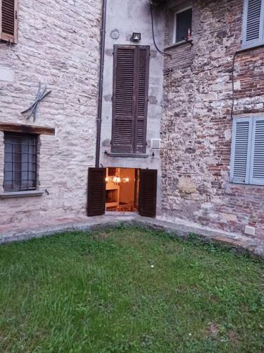 a stone building with a door and a grass yard at Casa vacanza Raffaela in Gubbio