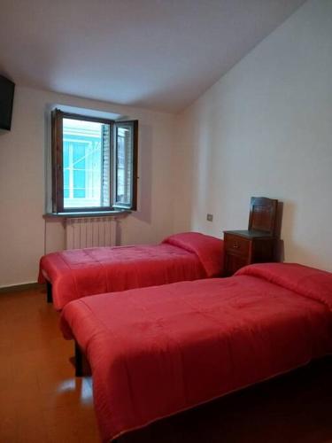 cztery czerwone łóżka w pokoju z oknem w obiekcie Casa vacanza Raffaela w mieście Gubbio