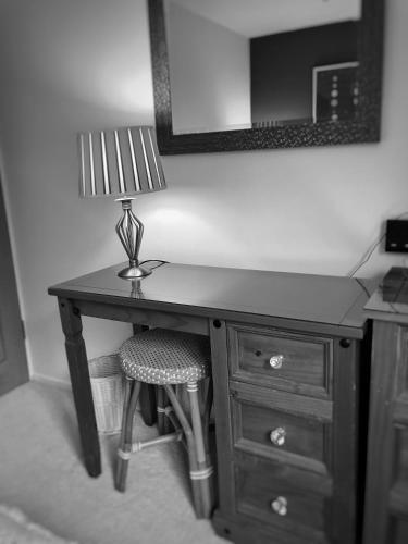 einen Schreibtisch mit einer Lampe und einem Stuhl in einem Zimmer in der Unterkunft Bindons in Taunton