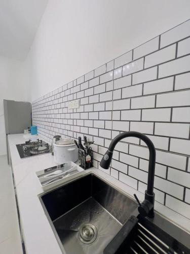 a kitchen with a sink and a white brick wall at NOOR Homestay Paddy View in Kangar