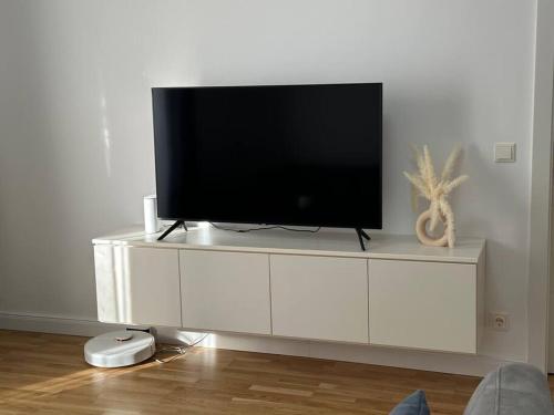 uma televisão em um centro de entretenimento branco em uma sala de estar em Gemütliche 2- Zimmer Apartment Nähe Neu Donau em Viena