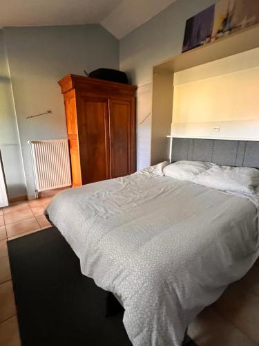 Halte en Provence في Peyruis: غرفة نوم مع سرير أبيض كبير وخزانة خشبية
