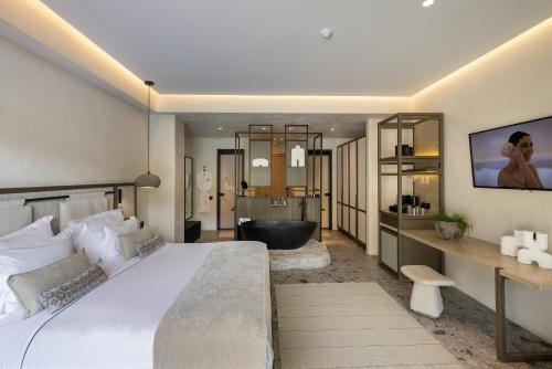 a bedroom with a large bed and a bath tub at Aeonic Suites and Spa in Mýkonos City