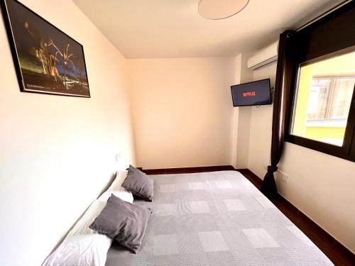 a bedroom with a bed with a tv on the wall at MT Nuevos Apartamentos y Suites con baño privado in Mataró