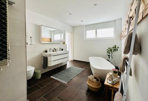 łazienka z umywalką, toaletą i wanną w obiekcie Haus am Bodensee mit Sicht - Stilvoller Luxus w mieście Ermatingen