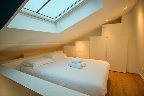 a bedroom with a white bed with a skylight at Le Louis XVI - Loft in the clouds in the heart of Nancy in Nancy