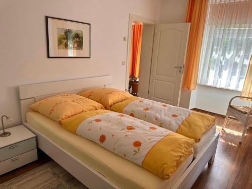 Schlafzimmer mit einem Bett mit gelber und orangefarbener Bettwäsche in der Unterkunft Ferienwohnung Seerose in Sassnitz