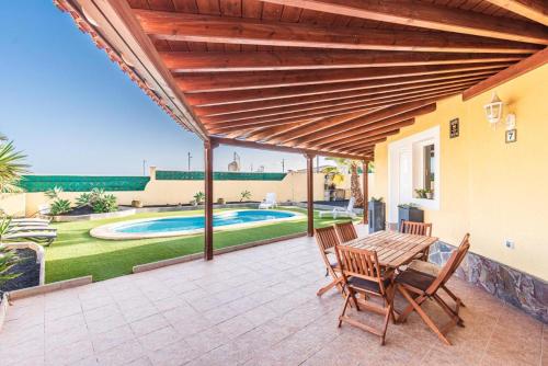 un patio con tavolo e sedie e una piscina di Villa Sophia a Caleta De Fuste