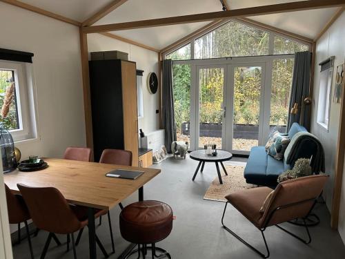 a living room with a table and chairs and a couch at Schitterend 4 persoons Tinyhouse met HOTTUB aan de bossen in Putten 4-16 in Putten