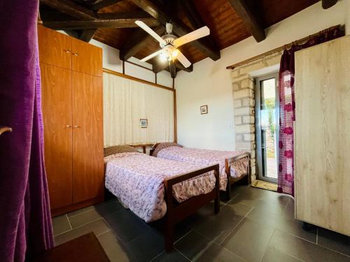 a bedroom with two beds and a window at Stone Maisonettes in Aigio