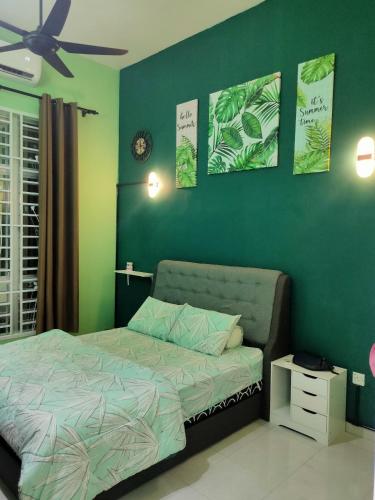 1 dormitorio con cama y pared verde en Amani Homestay, en Melaka