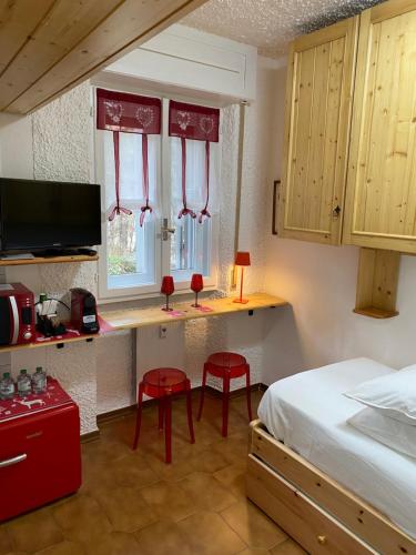 een slaapkamer met een bed en een bureau met 2 rode stoelen bij Suite Neve in Madesimo