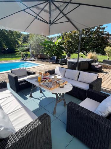 un patio avec une table, des chaises et un parasol dans l'établissement La Tour Carrée, à Nenon