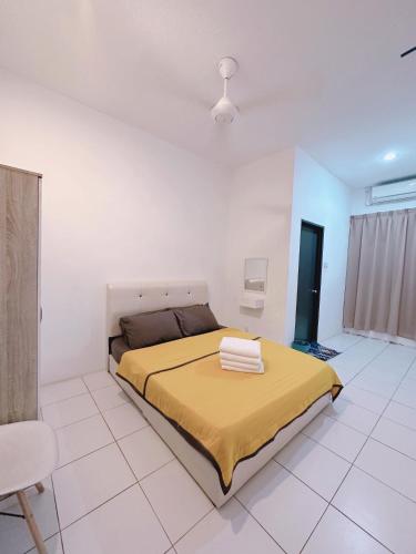 a bedroom with a bed with a yellow blanket on it at Aidee Homestay Taman Ria Height in Tawau
