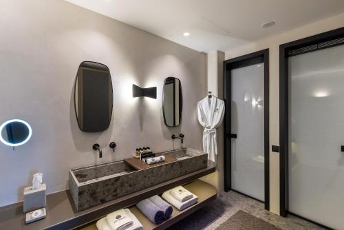 a bathroom with a sink and mirrors on the wall at Aeonic Suites and Spa in Mýkonos City