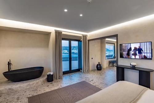 a bathroom with a tub and a television and a bed at Aeonic Suites and Spa in Mýkonos City