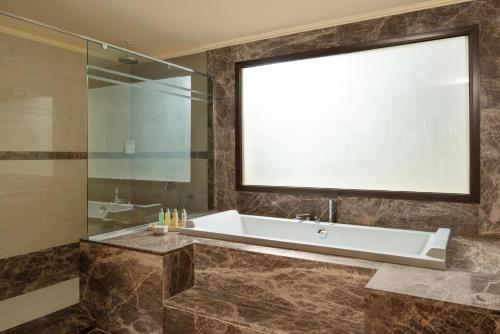 a bathroom with a tub and a glass shower at Jaz Oriental, Almaza Bay in Marsa Matruh