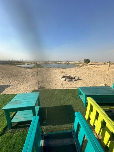 two blue and yellow tables and chairs next to a beach at Oasis Caravan in Dubai