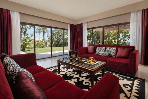 a living room with a red couch and a coffee table at JAZ Oriental, Almaza Bay in Marsa Matruh