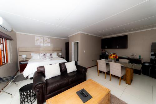 a bedroom with a bed and a couch and a table at Kleinplasie Guesthouse in Springbok
