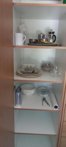 a white cabinet with plates and dishes on it at Coco's Hamlet Self Catering Accommodation in Prince Alfreds Hamlet