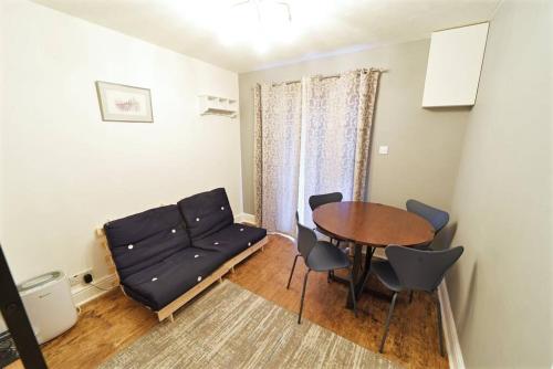 een woonkamer met een bank en een tafel bij Cosy Studio - Private Entrance Bishop’s Stortford in Bishops Stortford