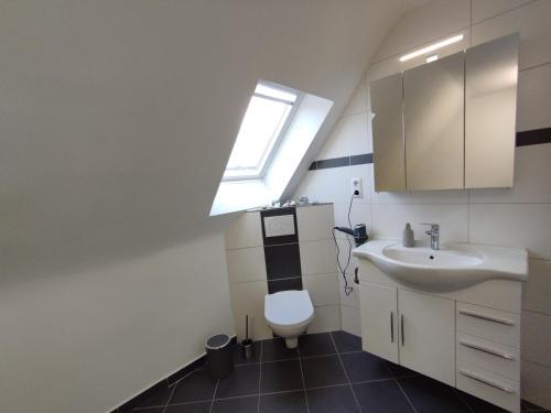 a bathroom with a toilet and a sink and a window at Ferienwohnung Schmidt in Schüttorf