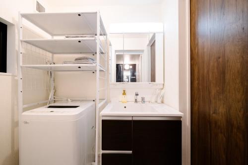 a small white bathroom with a sink and a mirror at Maison Novel under Skytree in Tokyo