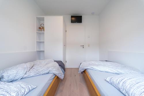 2 Betten in einem Zimmer mit weißen Wänden in der Unterkunft Ferienhaus Zum Kuckuck, Wng 2, Urlaub im Eichsfeld in Kallmerode
