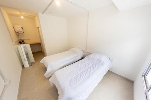 2 camas en una habitación pequeña con sábanas blancas en Petit apart en Villa María