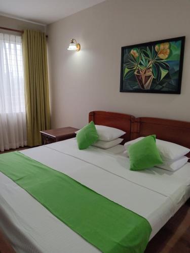 1 dormitorio con 1 cama grande con almohadas verdes en Rockwood Apartment Colombo 7, en Colombo