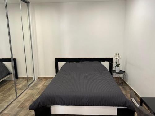 Ce lit se trouve dans un dortoir doté d'un cadre de lit noir. dans l'établissement Joli appartement avec chambre et grande terrasse à deux pas de la mer, à Sausset-les-Pins