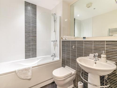 a white bathroom with a toilet and a sink at Apartment 13 in Swansea