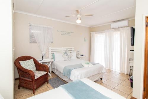 a bedroom with two beds and a chair and a tv at Gastehuis 17 in Bloemfontein