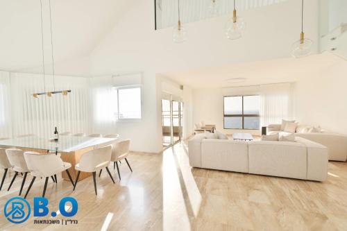 a white living room with a table and a couch at על הים in Netanya