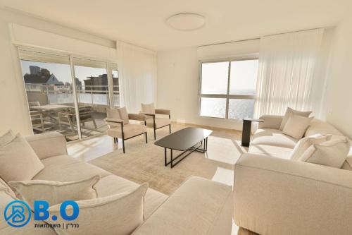 sala de estar con muebles blancos y mesa en על הים, en Netanya