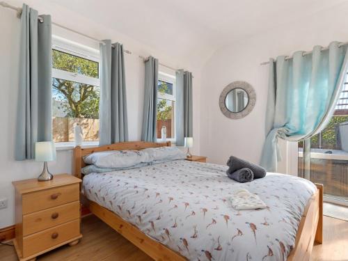 a bedroom with a bed with blue curtains and a window at The Cwtch in Pembrokeshire