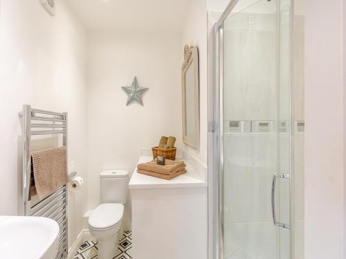 a white bathroom with a shower and a toilet at Adair Cottage in Wigglesworth