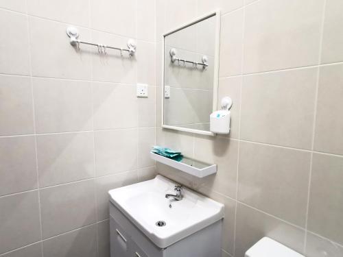 ein weißes Badezimmer mit einem Waschbecken und einem Spiegel in der Unterkunft pen kyu house2 