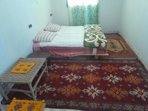 a bedroom with a bed and a table and rug at Auberge chez hammadi in Zagora