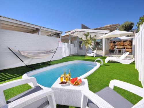 a backyard with a pool and chairs and a table with drinks at לה פאצה - בריכה פרטית in Had Nes
