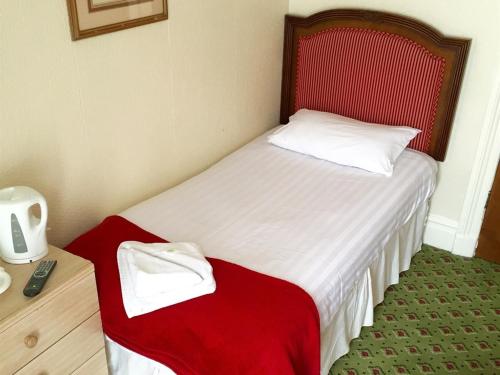 a small bedroom with a bed with a red headboard at The Melville Hotel in Blackpool