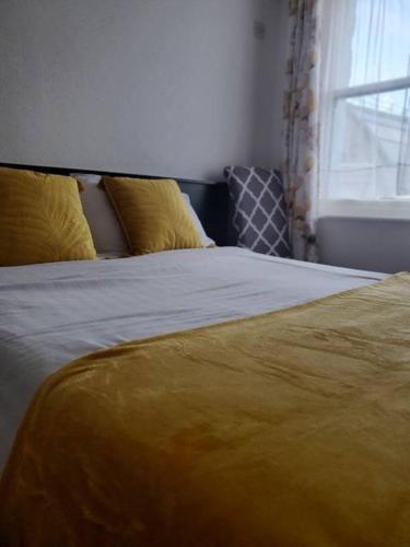 a bed with a yellow blanket and a window at The Melville Hotel in Blackpool