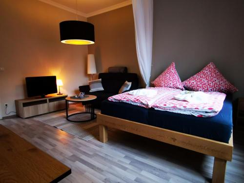 a bedroom with a bed with pink pillows and a couch at City Apartment Aurich - Ostfriesland in Aurich