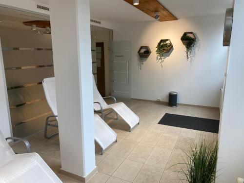 Zimmer mit weißen Stühlen und Gemälden an der Wand in der Unterkunft FeWo Waldsee mit Pool und Sauna inklusive in Sankt Englmar