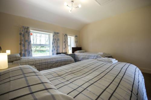 a bedroom with two beds and a window at Exclusive Use Moor Grange Farm 13 Bedrooms in Buxton